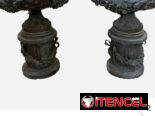 Urna de bronce vintage con detalles de flores y volutas sobre pedestal