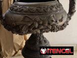 Urna de bronce vintage con detalles de flores y volutas sobre pedestal