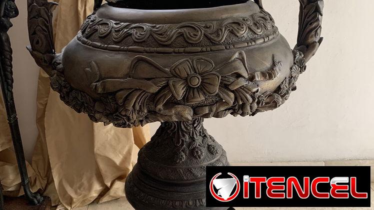 Urna de bronce vintage con detalles de flores y volutas sobre pedestal