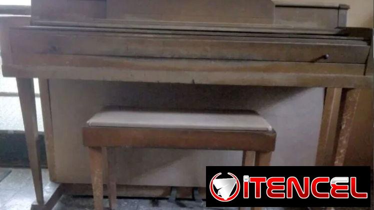 Piano acústico Wurlitzer con su banqueta portalibros, ideal para estudio.