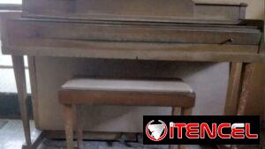 Piano acústico Wurlitzer con su banqueta portalibros, ideal para estudio.